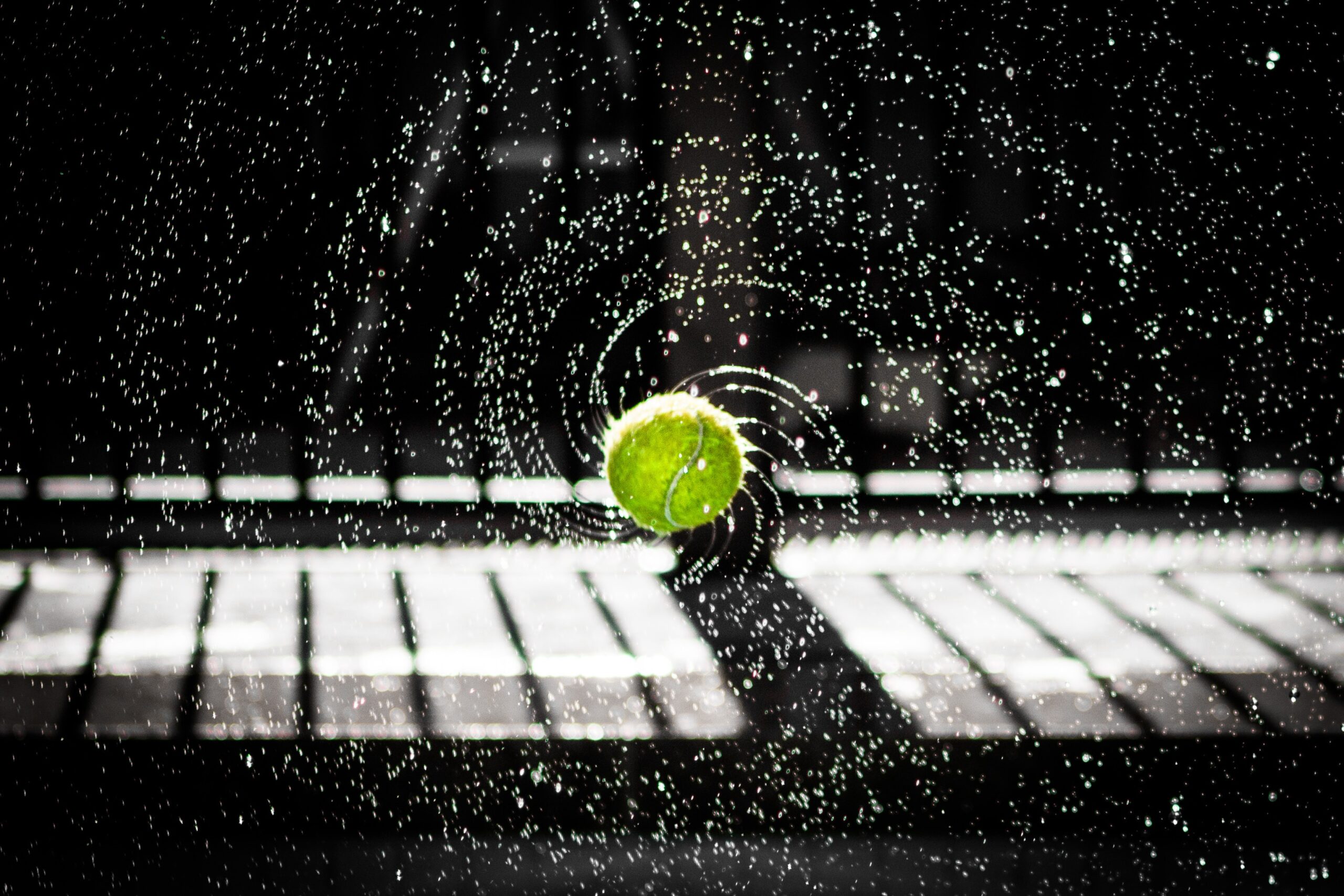 Tennis Whites - a spinning wet tennis ball trails droplets of water off its surface in perfect spirals